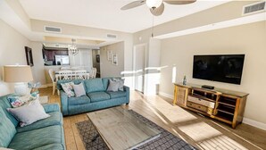 Una sala de estar con un sofá azul verdoso, una mesita de centro y un televisor sobre un mueble de madera.
