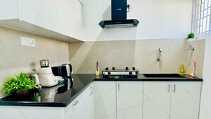 Una cocina moderna con armarios blancos, encimera negra, estufa integrada y cafetera.