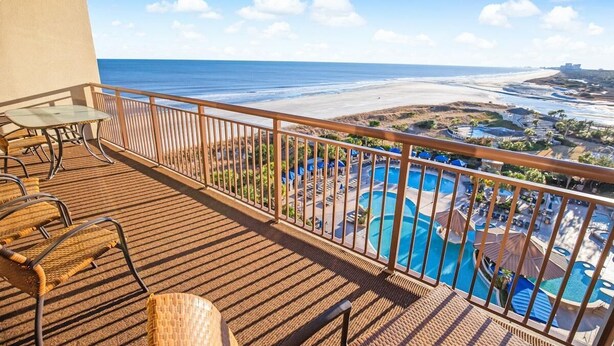 Een balkon met uitzicht op een strand en een zwembad.