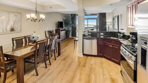 Une cuisine moderne avec des meubles en bois foncé, des appareils électroménagers en acier inoxydable et un coin repas comprenant une table et des chaises en bois.