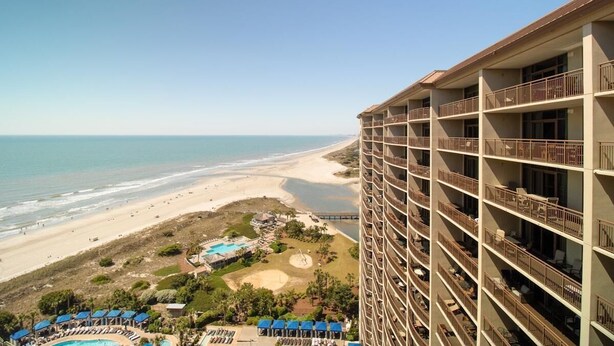 Un hotel de gran altura con múltiples balcones con vistas a la playa y al océano.