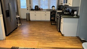 A compact kitchen with white cabinets, a stainless steel refrigerator, a microwave, and a stove. - 5 Bedroom Apartment Hotel (Keansburg)
