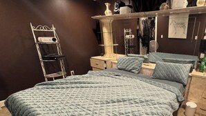 A bedroom with a large bed, a bedside table, a mirror, and a wardrobe. - 5 Bedroom Apartment Hotel (Keansburg)