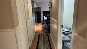 A hallway leading to a living area with a sofa, a rug, and a wall-mounted light fixture. - 5 Bedroom Apartment Hotel (Keansburg)