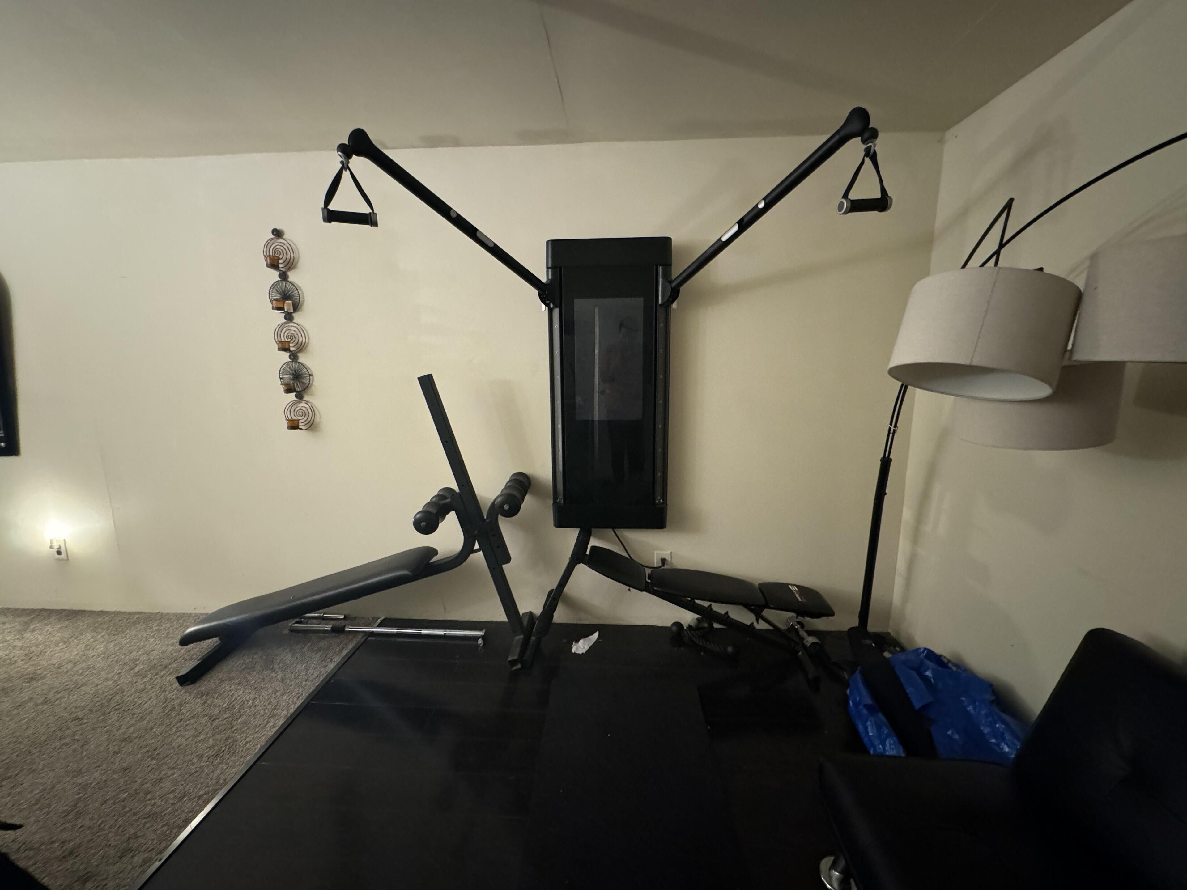 Una palestra con attrezzature per esercizi, una TV a muro e una lampada.