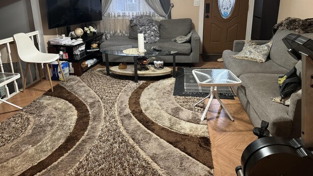 A living room with a sofa, a coffee table, a TV, and a door with a stained glass window. - 5 Bedroom Apartment Hotel (Keansburg)