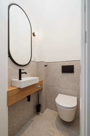 A compact bathroom with a white sink, black faucet, and a toilet.