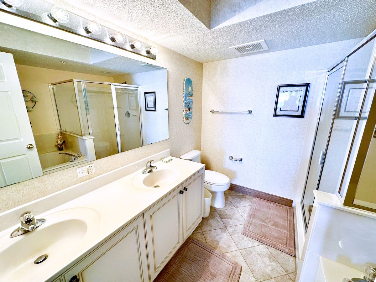 Un baño con lavamanos doble, inodoro y zona de ducha.