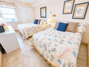 A bedroom with two beds, a desk, and a window with blinds. - Ashworth 1608 (North Myrtle Beach)