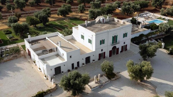 Un bâtiment blanc doté d’un toit plat, de nombreuses fenêtres et d’une piscine.