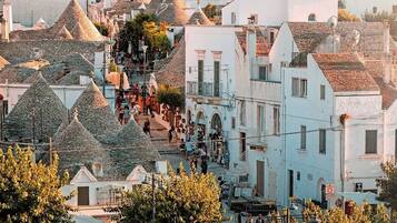 A town with white buildings and conical roofs, a central square with people, and a stop sign.