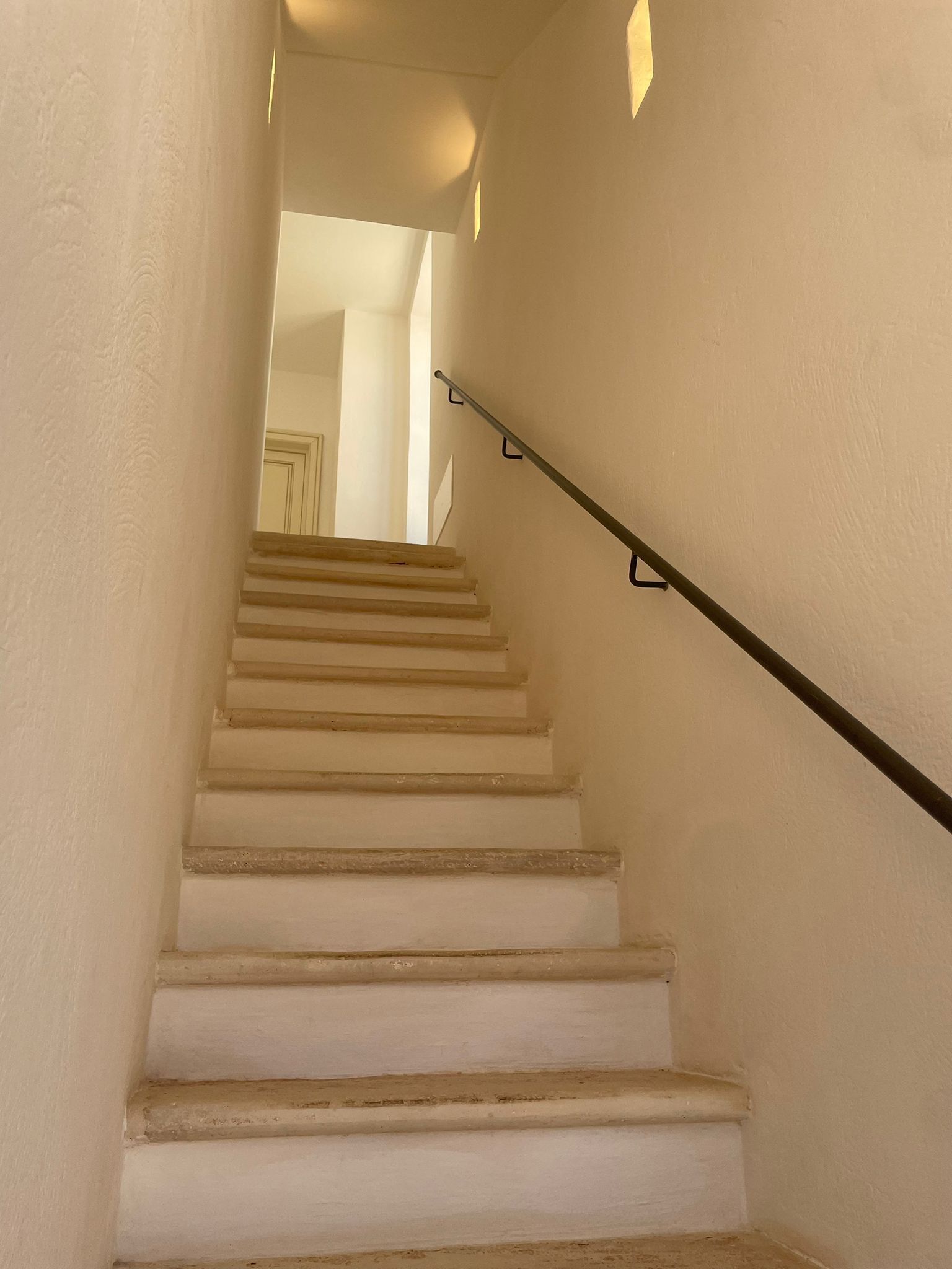 Un escalier avec une rampe, menant à un espace intérieur.