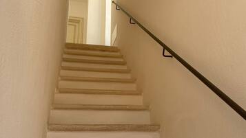 Un escalier avec une rampe, menant à un espace intérieur.