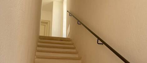 Un escalier avec une rampe, menant à un espace intérieur.