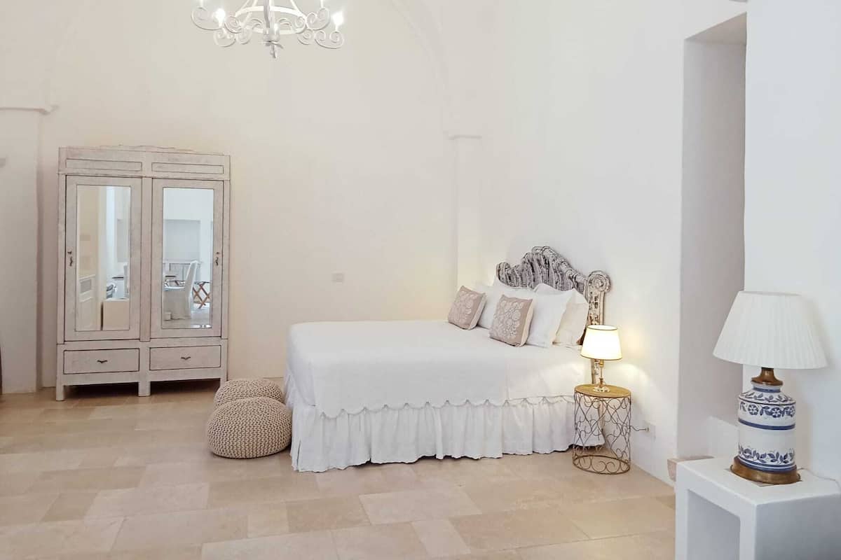 Ein Schlafzimmer mit einem Bett, Nachttischlampen, einem Kleiderschrank und einer Pendelleuchte.