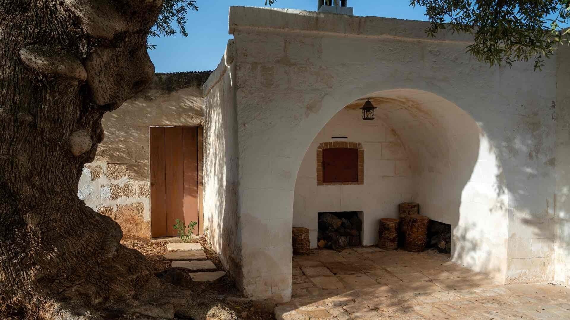 Un edificio de piedra con una puerta de madera, un arco de entrada y un pequeño farol.