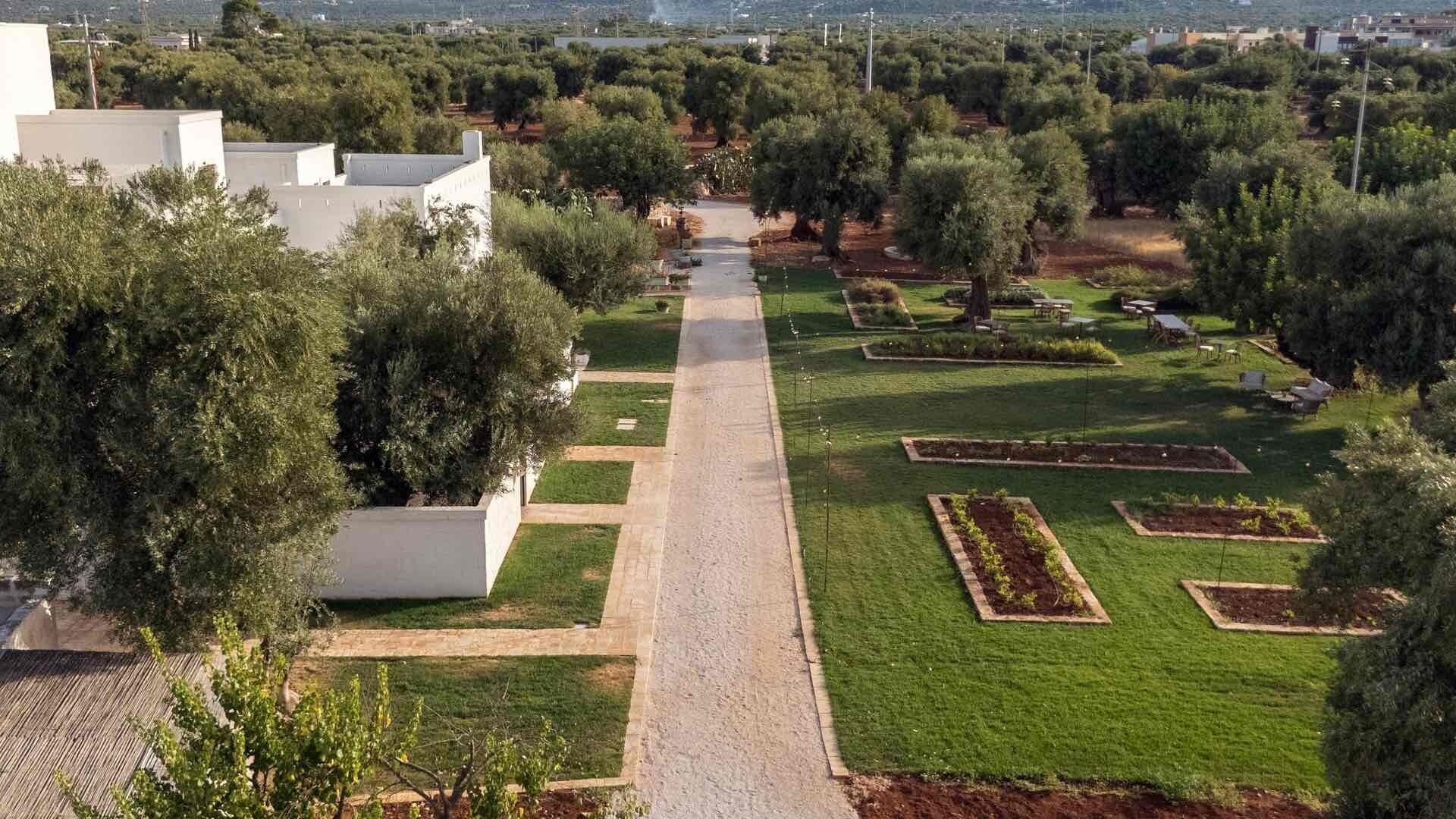 A landscaped garden with a central pathway, surrounded by neatly trimmed grass and trees.