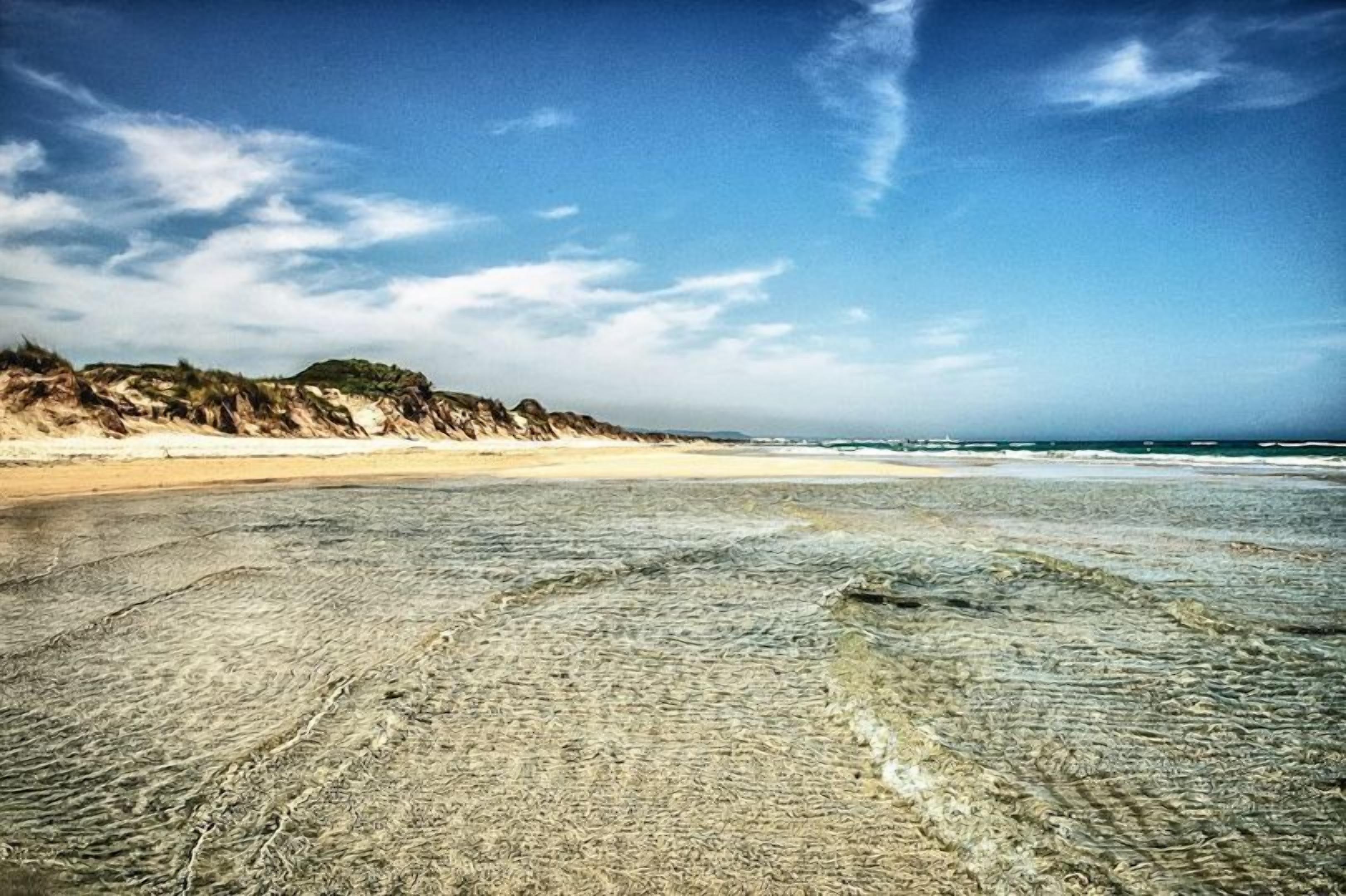 A beach with a sandy shore and a clear sky.