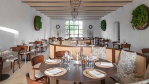 A restaurant with round tables, wicker chairs, and a central bar area.
