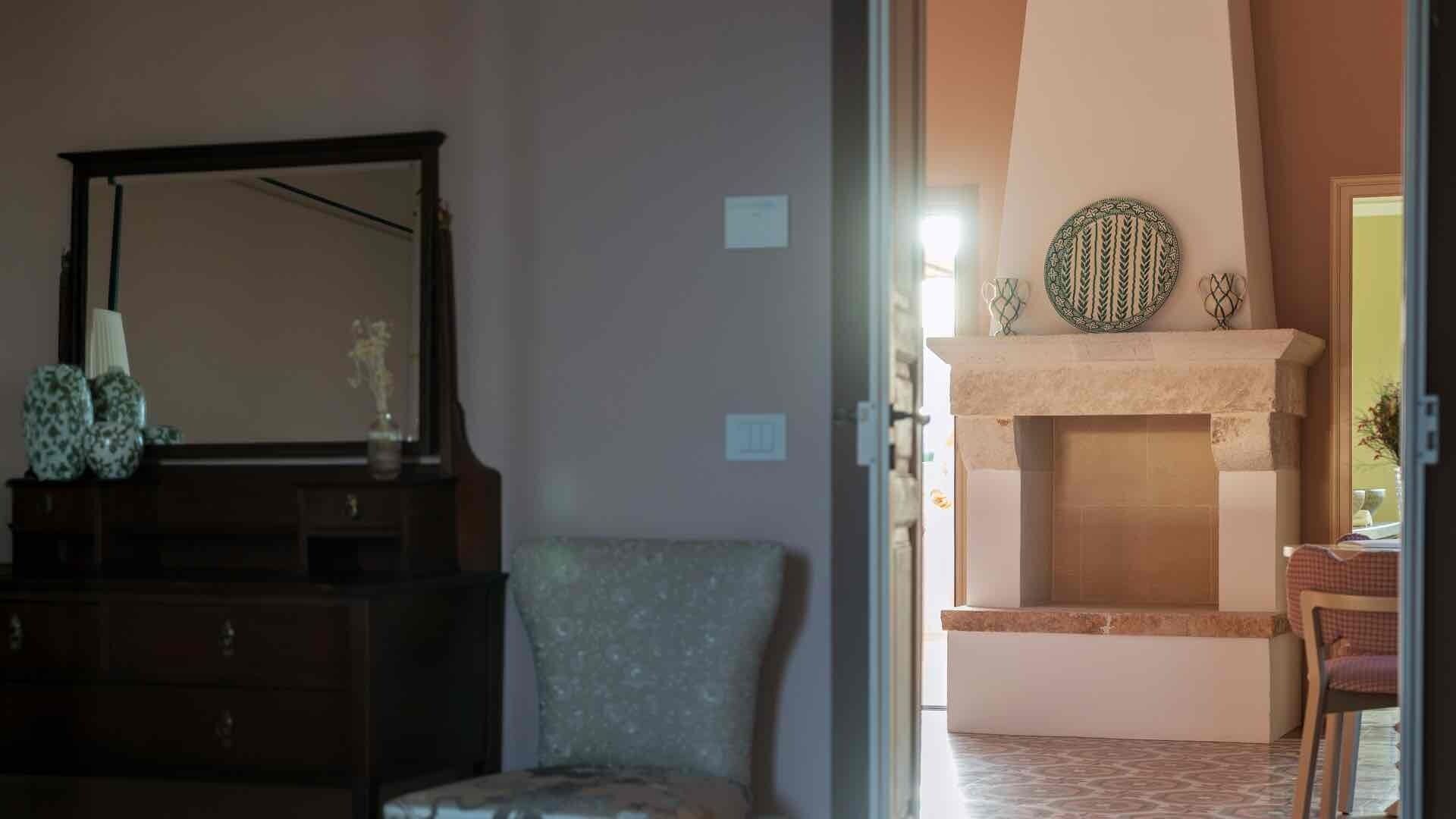 A room with a fireplace, a mirror, and a chair.