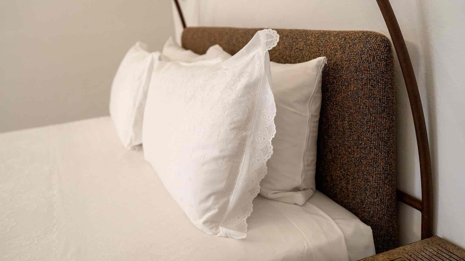 Ein Bett mit weißer Bettwäsche und einem braunen Kopfteil.