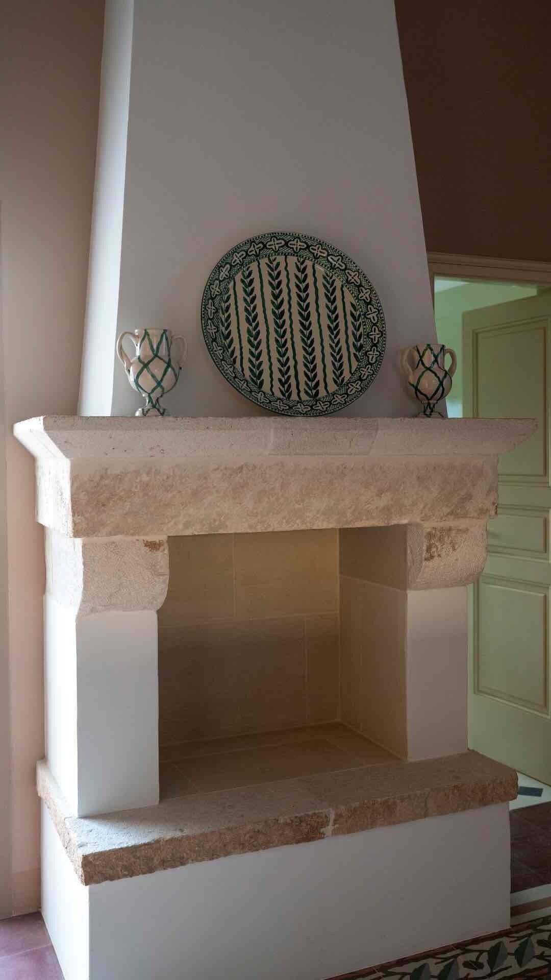 Une cheminée en pierre surmontée d’une plaque décorative.
