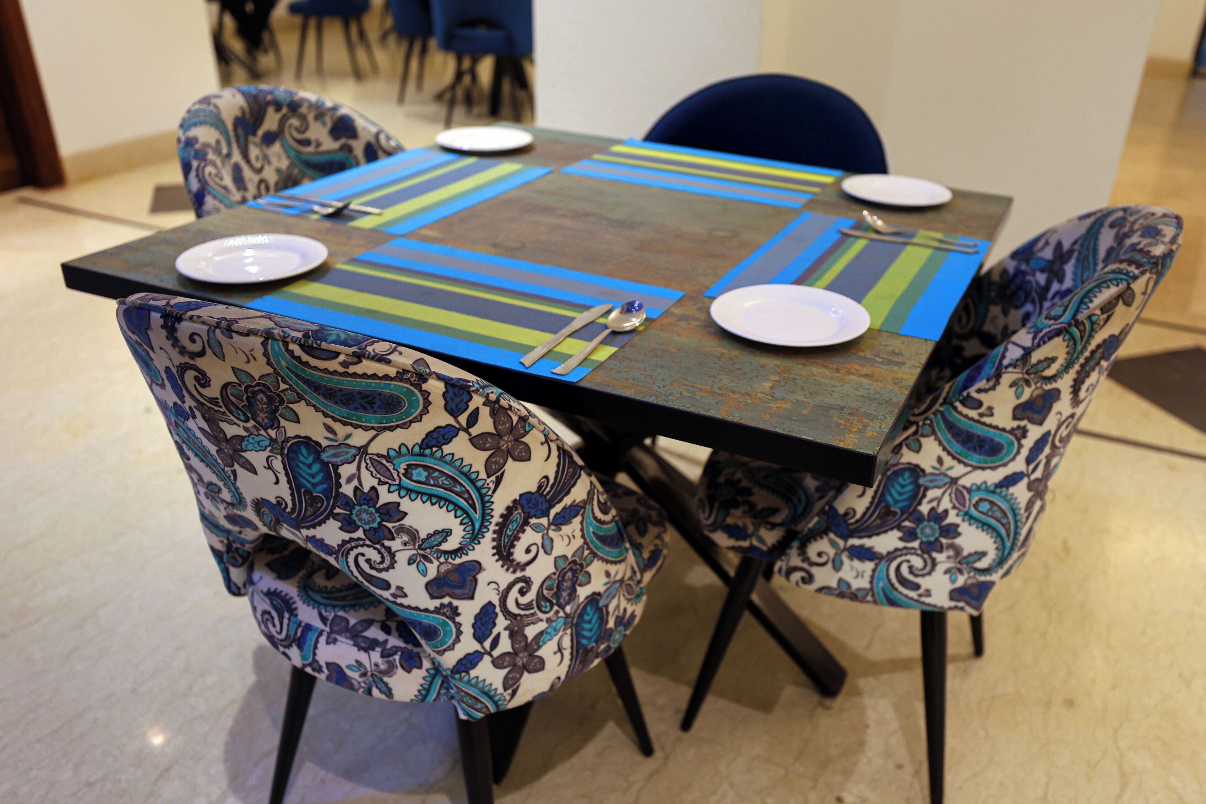 A dining table with a patterned table runner, surrounded by chairs with matching upholstery.