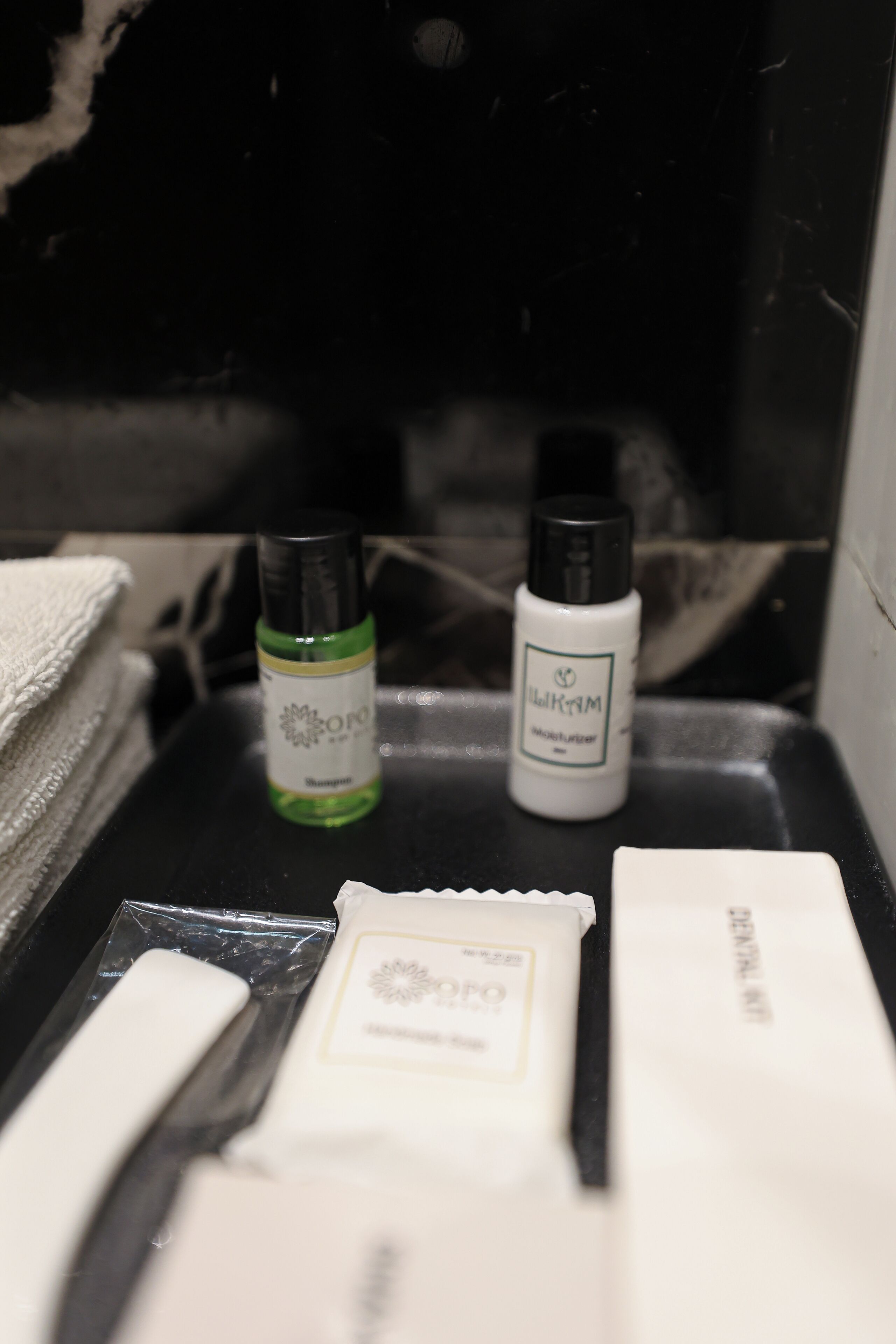 Un meuble-lavabo de salle de bain avec des articles de toilette, notamment un flacon vert, un flacon blanc et un savon.