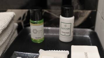 Un meuble-lavabo de salle de bain avec des articles de toilette, notamment un flacon vert, un flacon blanc et un savon.