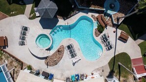 An aerial view of a swimming pool with lounge chairs and a hot tub.