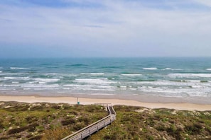 A coastal view with a sandy beach, a wooden boardwalk, and the ocean. - Seabatical- Hot Tub |  Community Pool | Pet Friendly (Port Aransas)