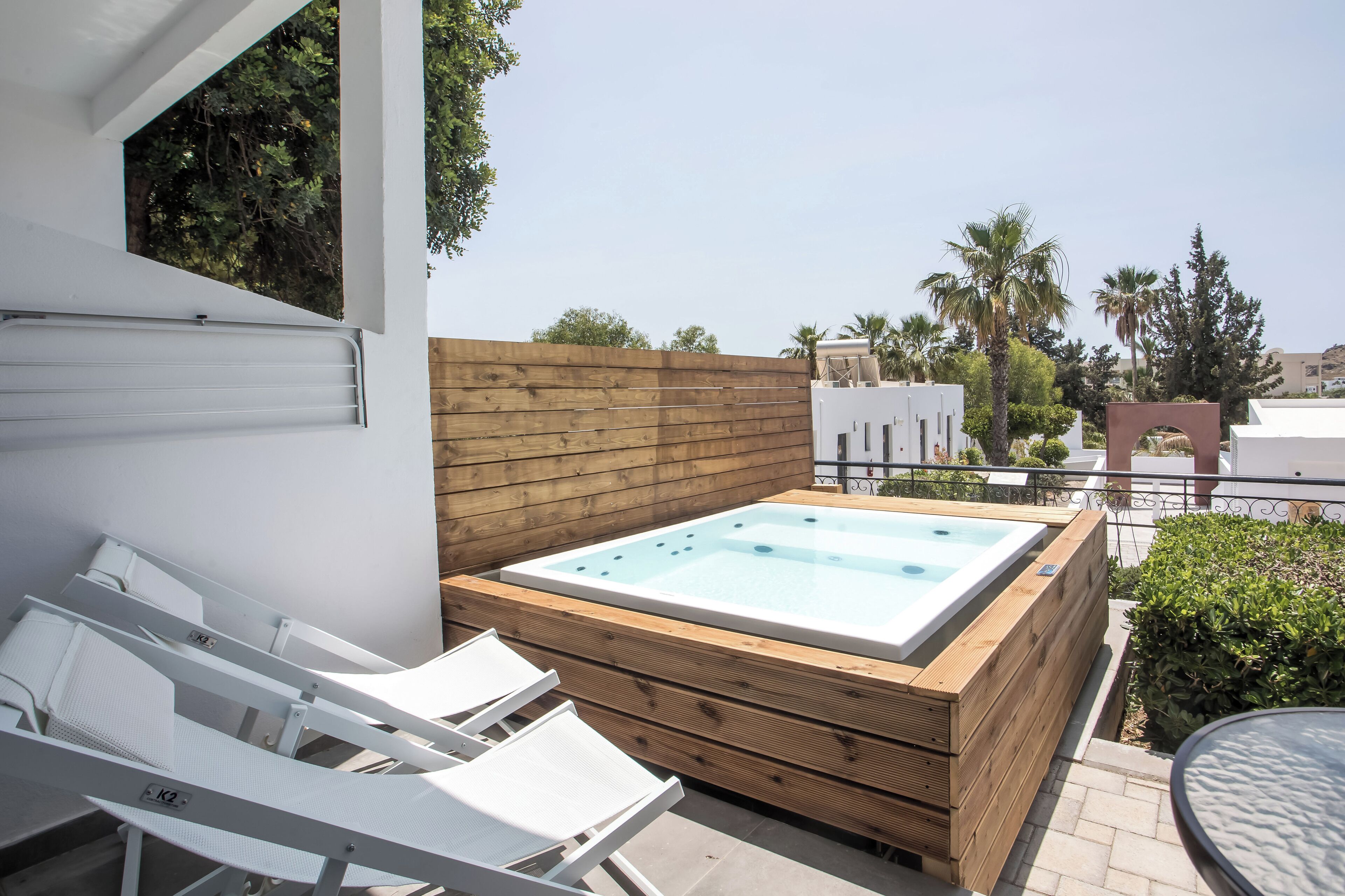 Terraza en la azotea con jacuzzi, sillones blancos para lounge y una cubierta de madera.