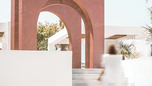 A modern building with a large archway and a staircase leading to a white structure. - Aiora Aqua Resort (Rhodes)