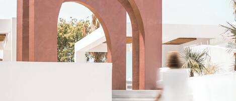 A modern building with a large archway and a staircase leading to a white structure.
