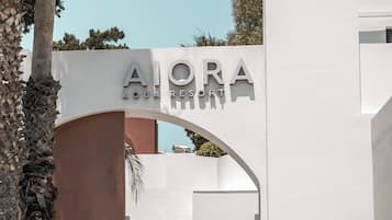 Una entrada moderna de edificio con el letrero "AIORA AQUA RESORT" y un camino que conduce a ella.