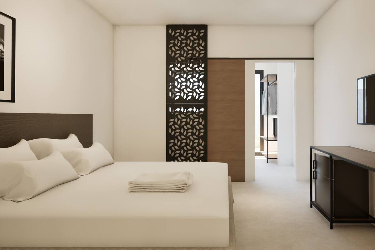 A modern hotel room with a neatly made bed, a television mounted on the wall, and a decorative panel.