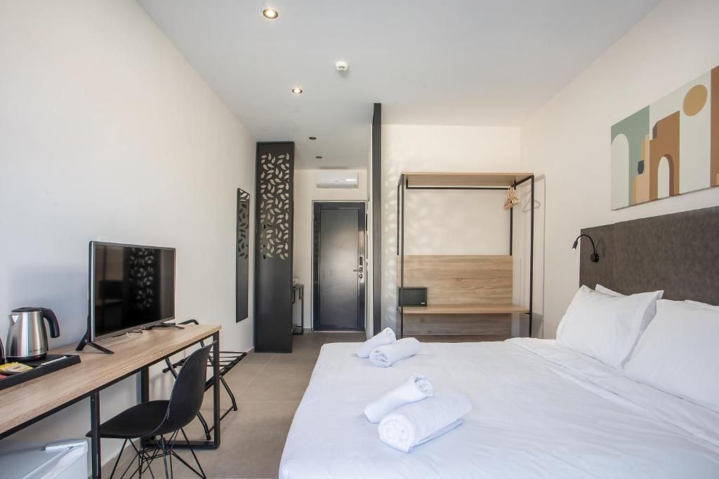 Habitación de hotel con cama, escritorio con computadora, televisor y zona de ducha.