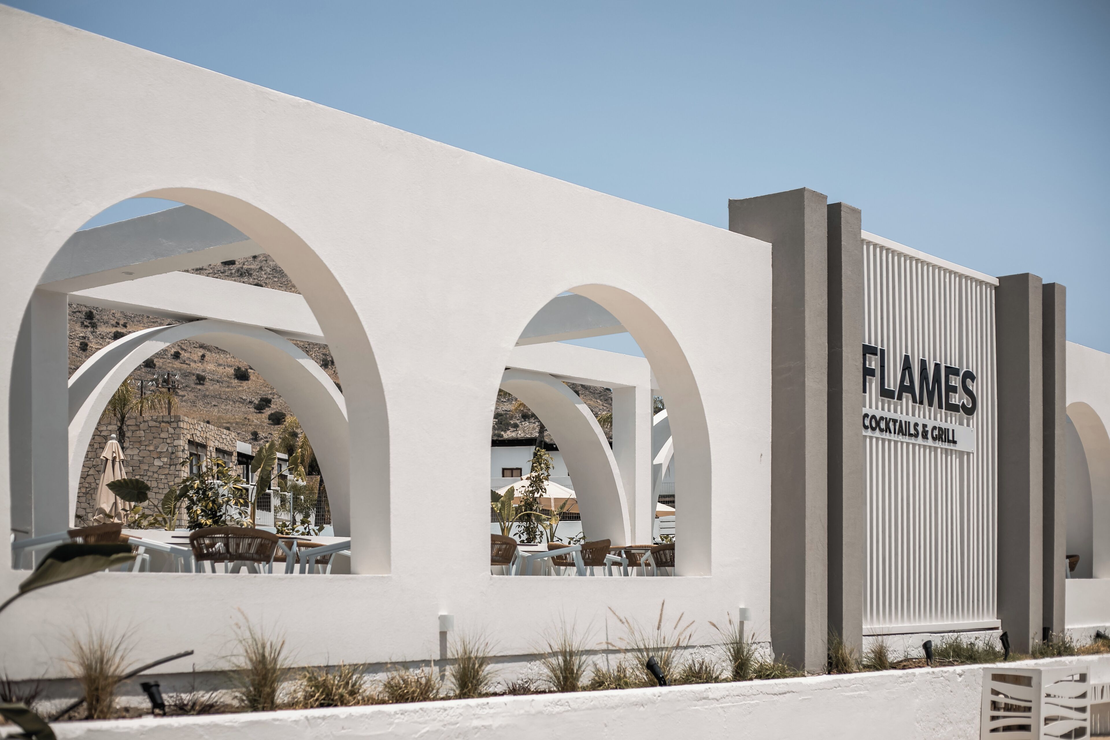 A modern building with a sign reading "FLAMES COCKTAILS & GRILL".