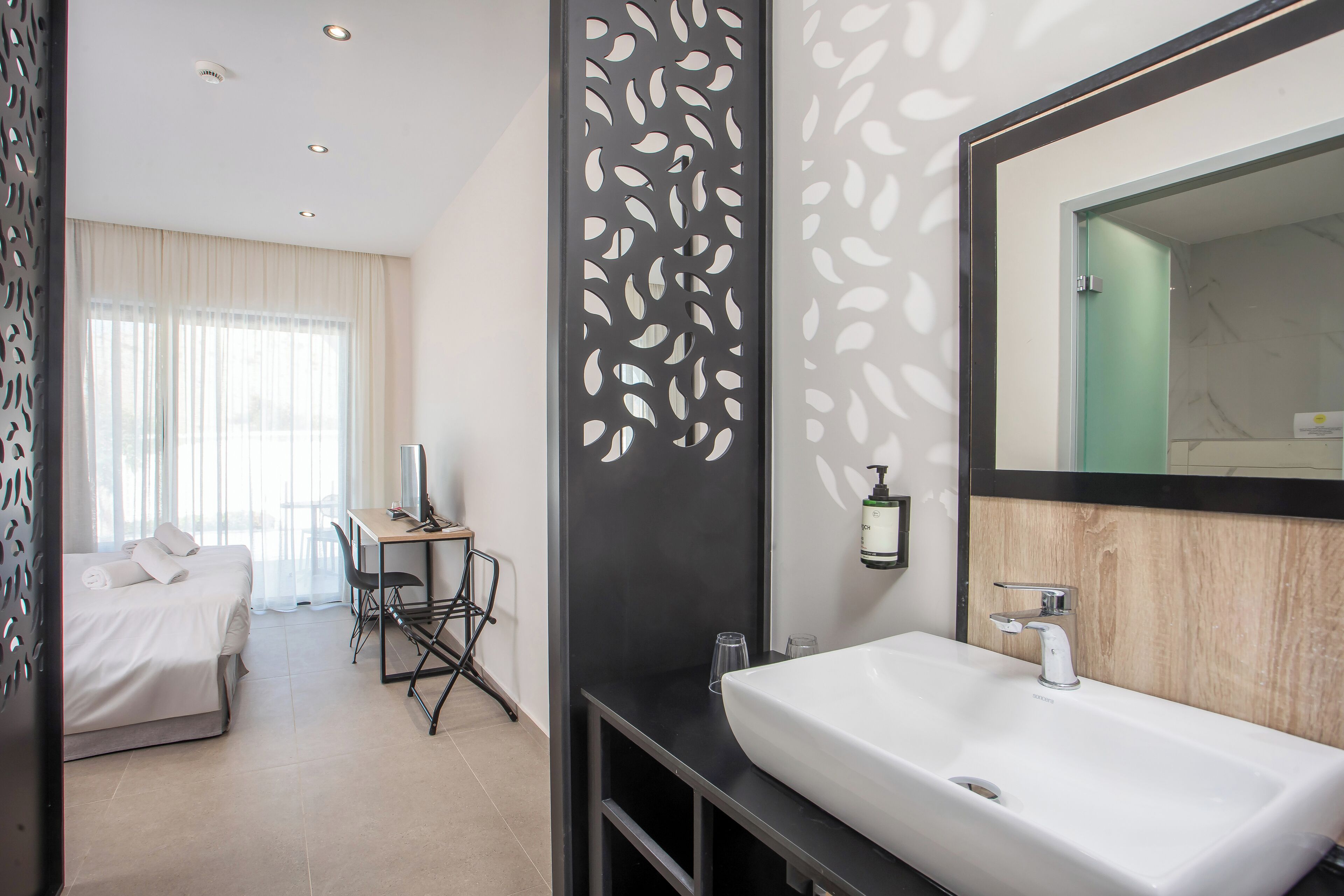 Una habitación de hotel moderna con cama, escritorio y baño.