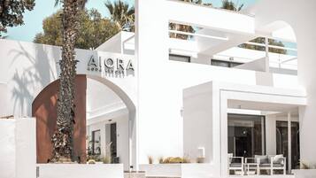 Un edificio moderno con fachada blanca, una entrada destacada con escalones y un letrero que dice "AIORA AQUA RESORT".