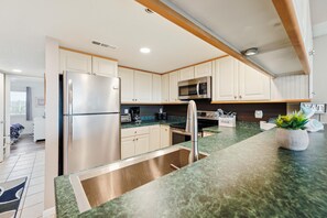 A modern kitchen with stainless steel appliances, a granite countertop, and white cabinetry.