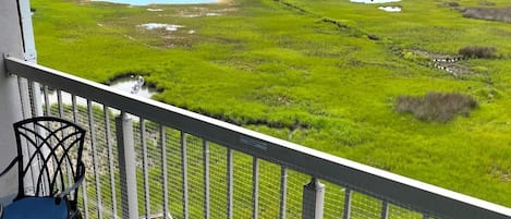 A balcony with a view of a coastal landscape, including water bodies and green fields.
