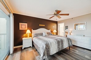 Un dormitorio con cama, mesitas de noche, ventilador de techo, cómoda y espejo.
