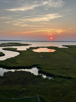 A natural landscape with a sunset over water and land, featuring ponds and grassy areas. - XPLORIE ACTIVITIES & LINENS INCLUDED*! Great 3BR bayfront condo on 79th Street with outdoor pool! (Ocean City)