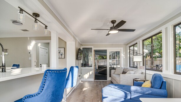 A spacious living area with a blue sofa, a coffee table, and a dining area with a bar stool. - Serene St Petersburg Home w/ Private Hot Tub (St. Petersburg)