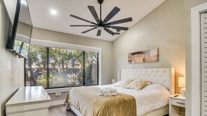 A bedroom with a large bed, a ceiling fan, a window, and a bedside table. - Serene St Petersburg Home w/ Private Hot Tub (St. Petersburg)
