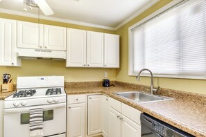 A kitchen with white cabinets, a stove, a dishwasher, a granite countertop, and a window with blinds. - Augusta Home w/ Fenced Yard - 4 Mi to Downtown! (Augusta)