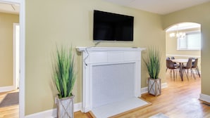 A living room with a fireplace, a mounted TV, and a dining area with chairs. - Augusta Home w/ Fenced Yard - 4 Mi to Downtown! (Augusta)