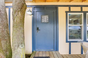 Una puerta azul con un ventanal pequeño, un timbre de metal y una cubierta de madera.