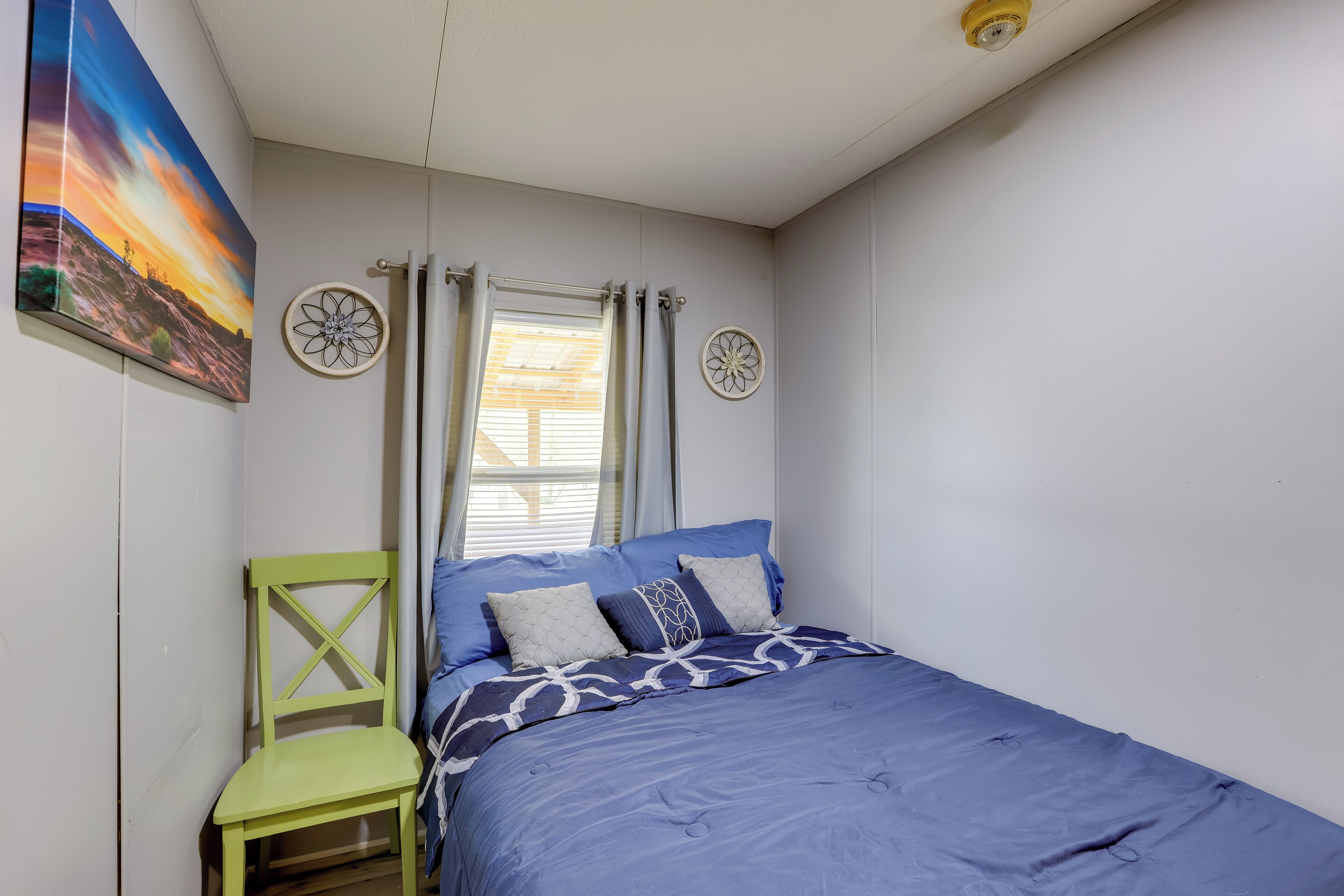 A bedroom with a bed, a chair, and a window with curtains.